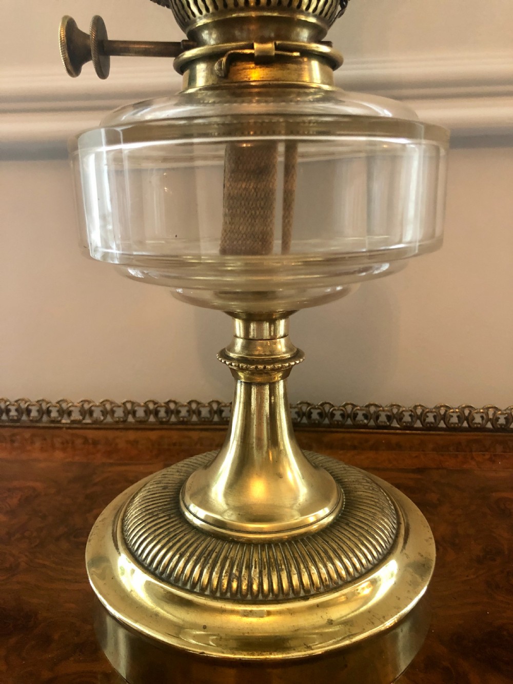 A Victorian oil lamp featuring a weighted brass base, clear glass reservoir, etched glass shade with a green crimped rim, and a tall clear glass chimney. View V
