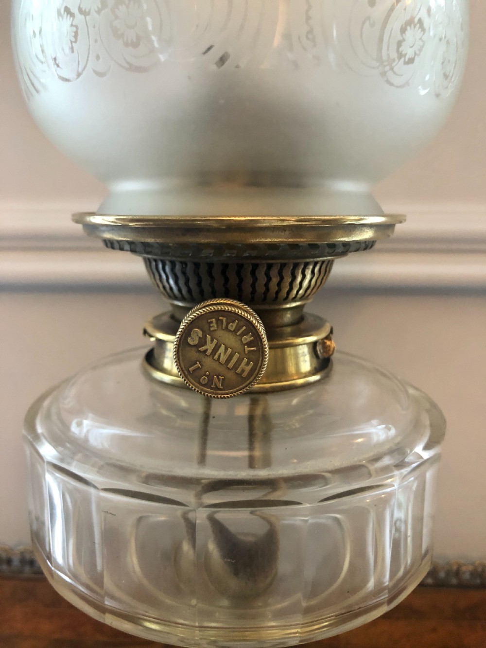 A Victorian oil lamp featuring a weighted brass base, clear glass reservoir, etched glass shade with a green crimped rim, and a tall clear glass chimney. View VI