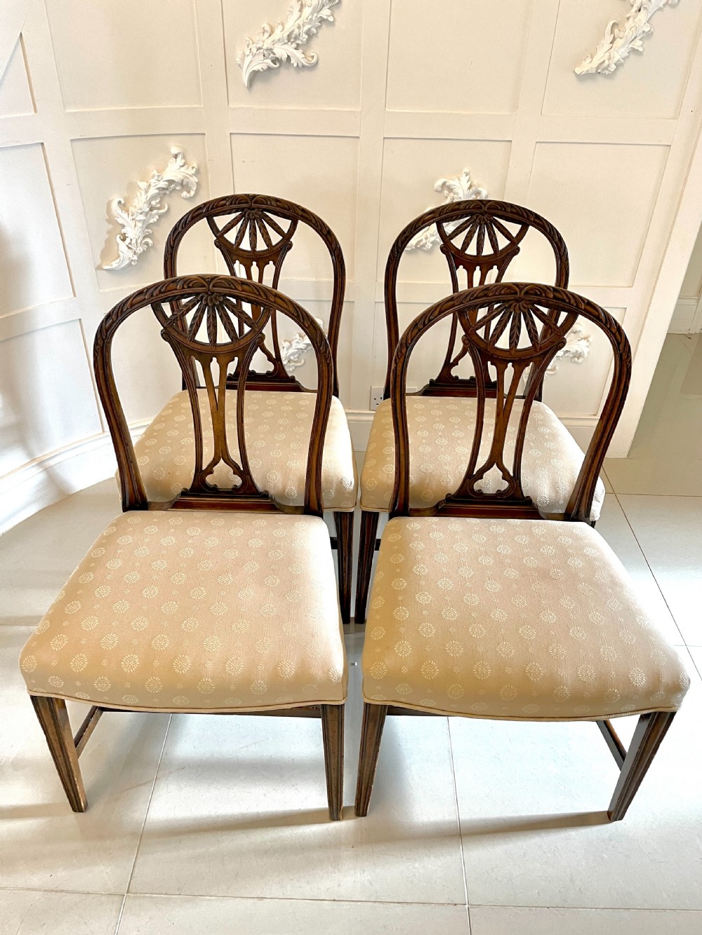 A set of four 19th-century mahogany dining chairs with carved openwork backrests and cream patterned upholstered seats.