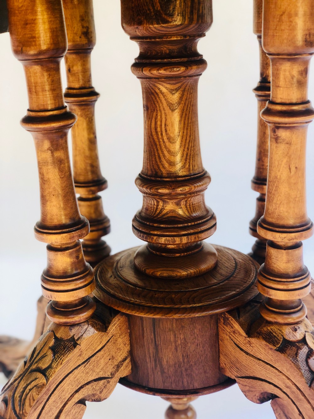 An oval Victorian walnut centre table featuring floral marquetry inlays on the top, supported by turned central columns and four carved legs on castors. View VII