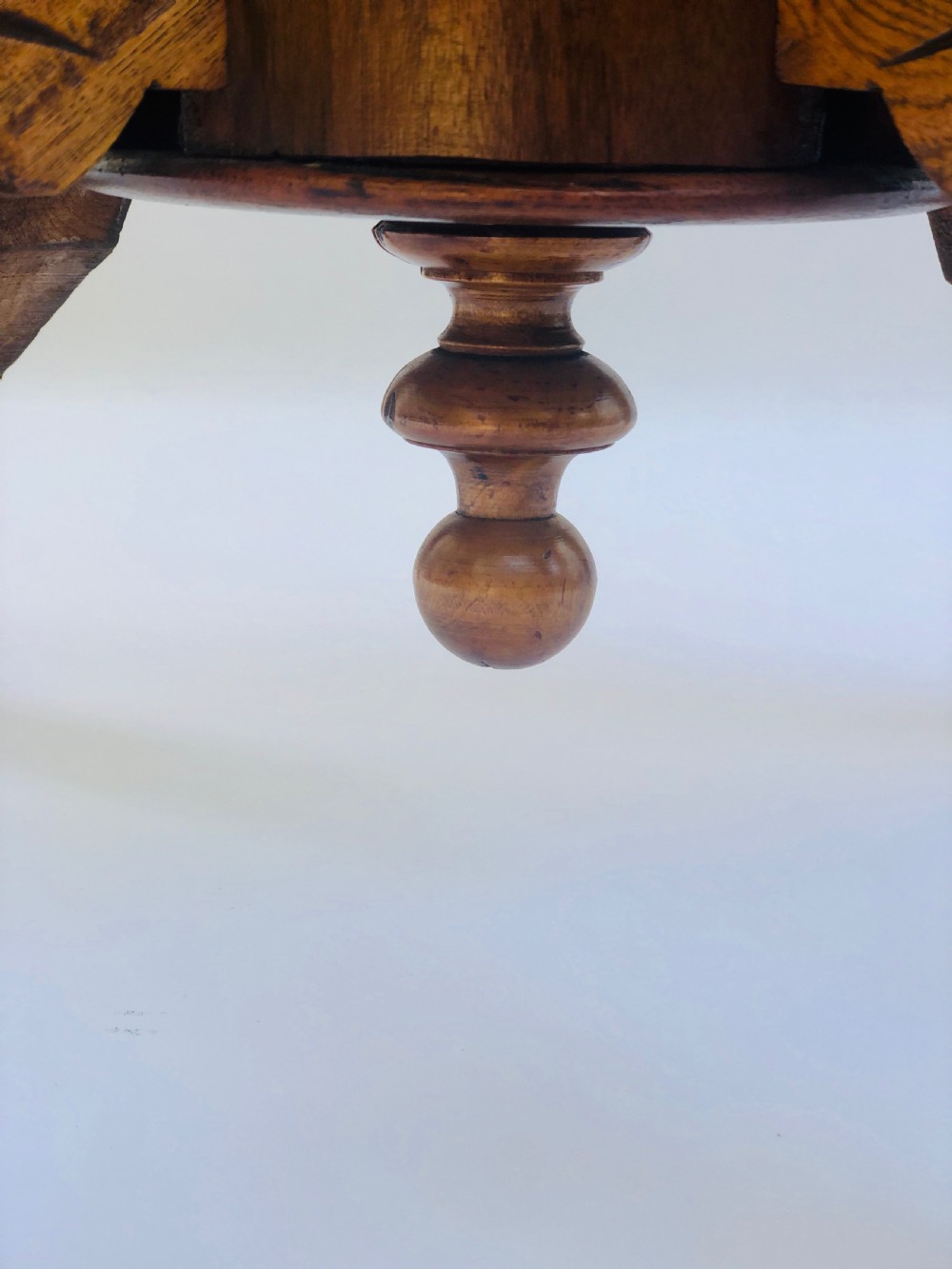 An oval Victorian walnut centre table featuring floral marquetry inlays on the top, supported by turned central columns and four carved legs on castors. View X