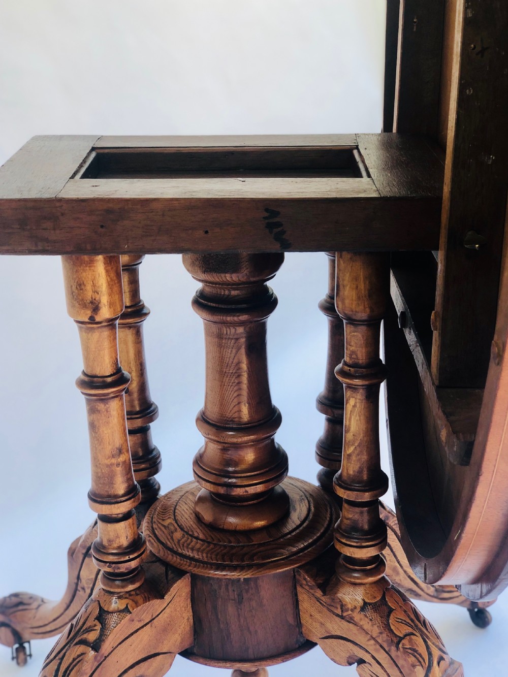 An oval Victorian walnut centre table featuring floral marquetry inlays on the top, supported by turned central columns and four carved legs on castors. View XI