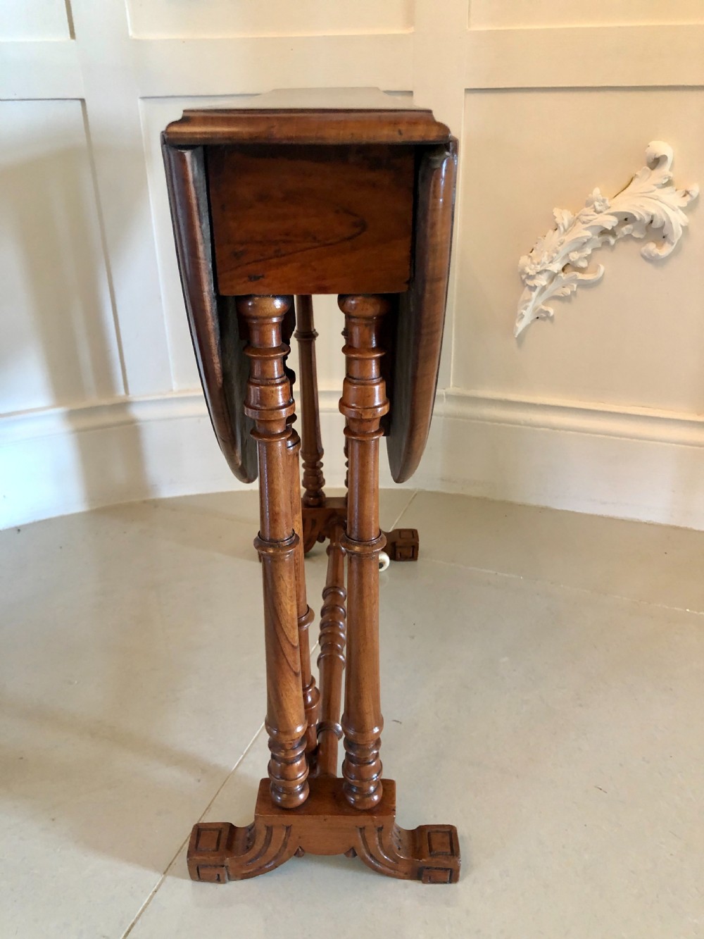 A Victorian walnut Sutherland table with drop leaves folded down, set on turned legs and ceramic castors. View III