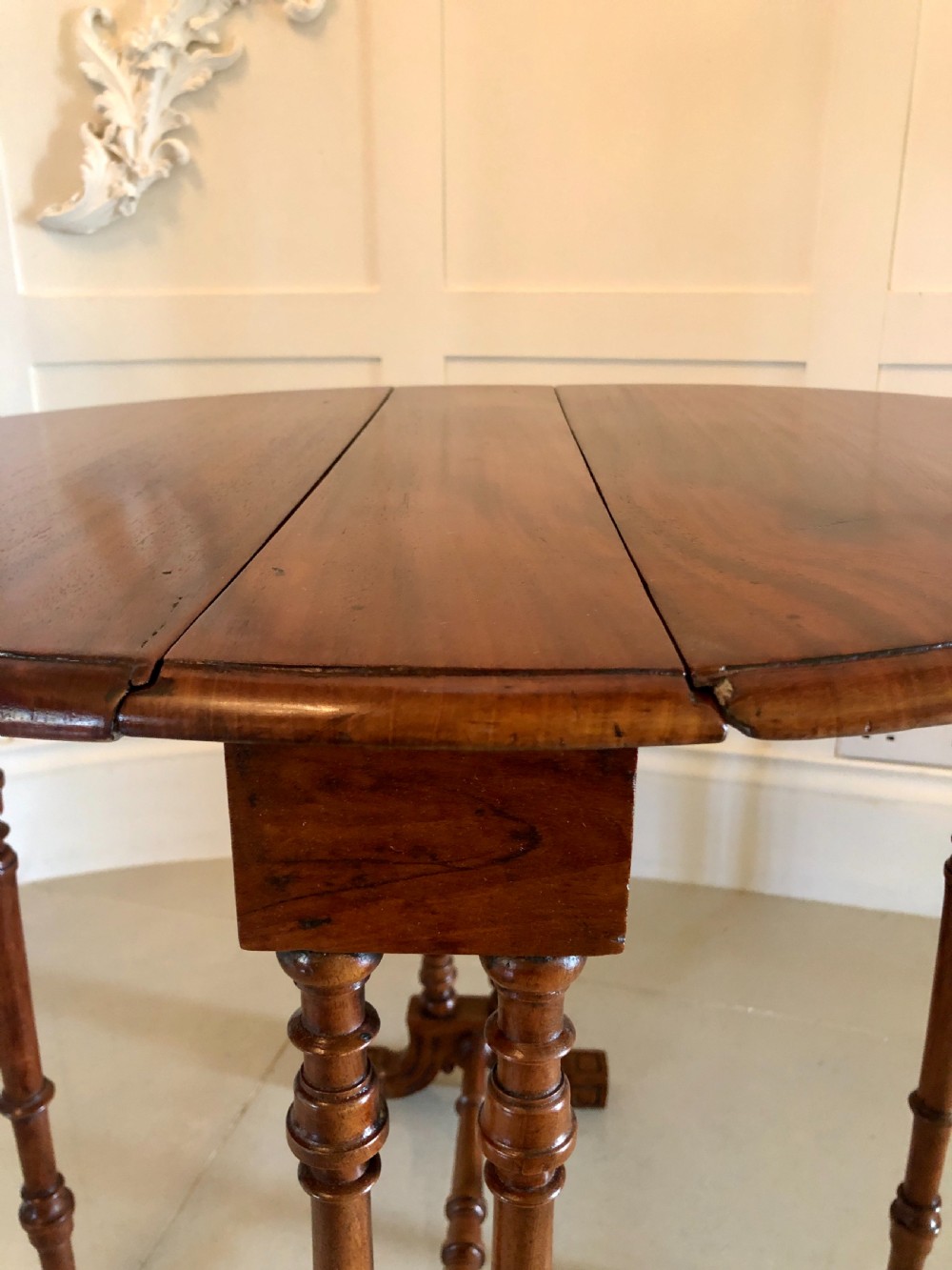 A Victorian walnut Sutherland table with drop leaves folded down, set on turned legs and ceramic castors. View IX