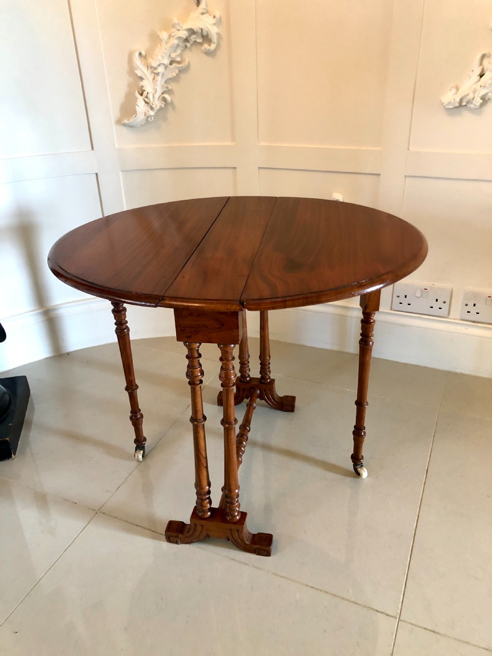 A Victorian walnut Sutherland table with drop leaves folded down, set on turned legs and ceramic castors. View X