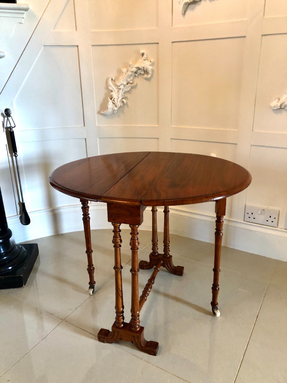 A Victorian walnut Sutherland table with drop leaves folded down, set on turned legs and ceramic castors. View XII