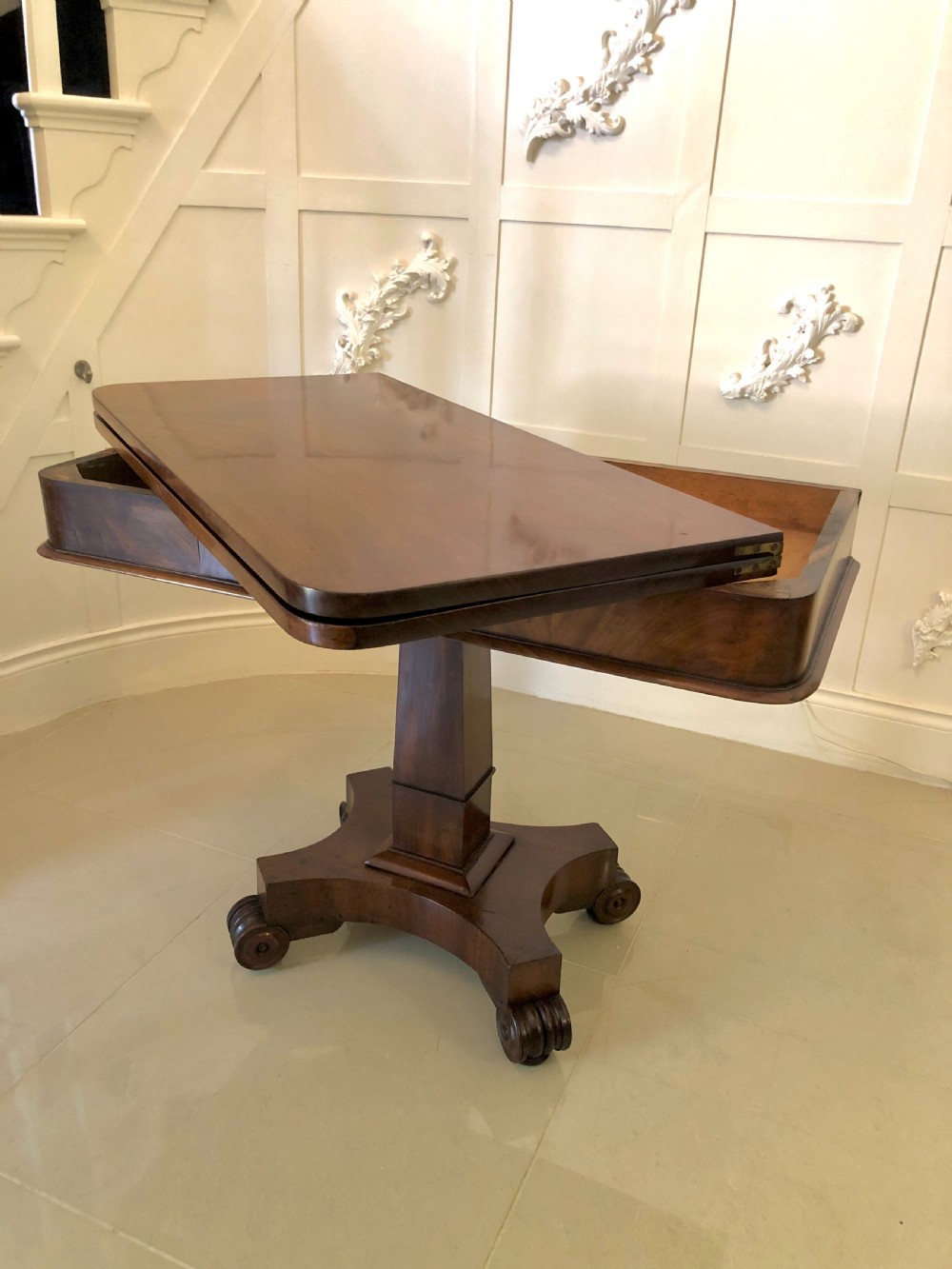 A William IV mahogany fold-over tea table featuring a rectangular swivel top on a square pedestal and a quadruped base with scrolled feet. View III