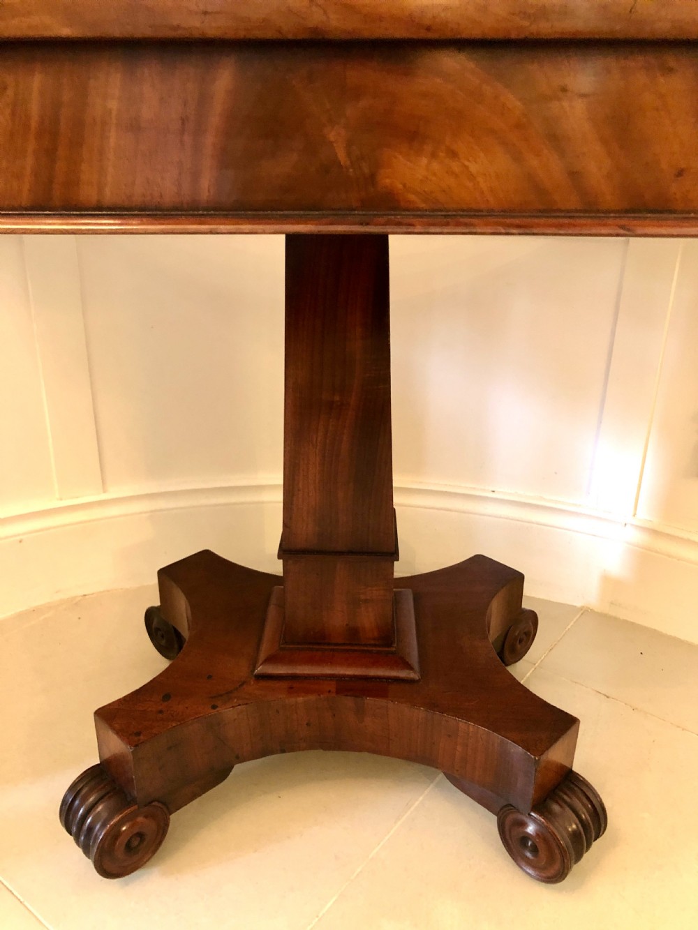 A William IV mahogany fold-over tea table featuring a rectangular swivel top on a square pedestal and a quadruped base with scrolled feet. View VI