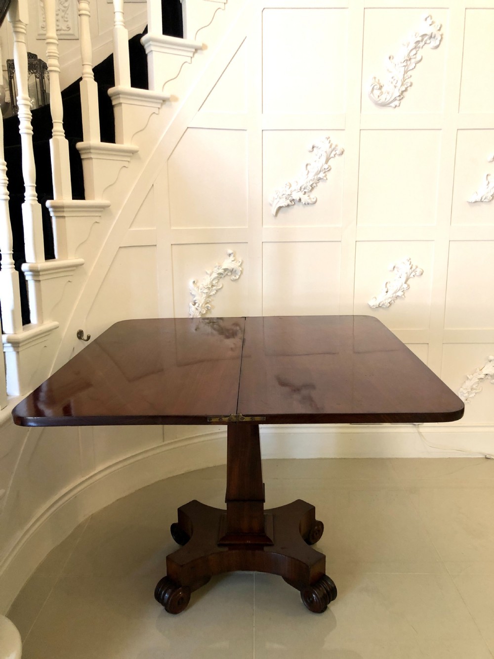 A William IV mahogany fold-over tea table featuring a rectangular swivel top on a square pedestal and a quadruped base with scrolled feet. View VII