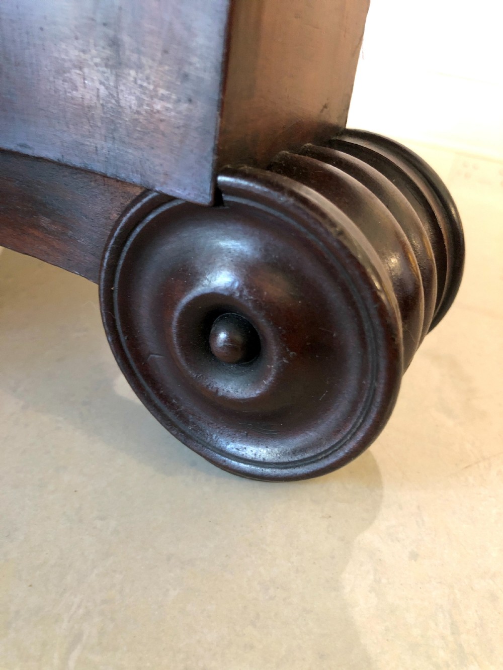 A William IV mahogany fold-over tea table featuring a rectangular swivel top on a square pedestal and a quadruped base with scrolled feet. View X