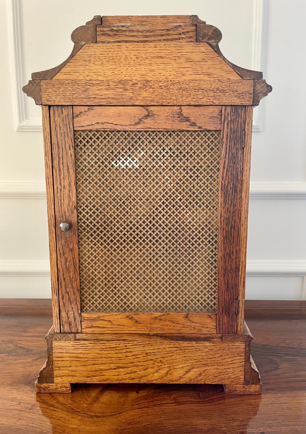 A Victorian carved oak bracket clock featuring a silvered engraved dial with Roman numerals, a chime-silent secondary dial, and carved gadrooned detailing along the top base. View VI