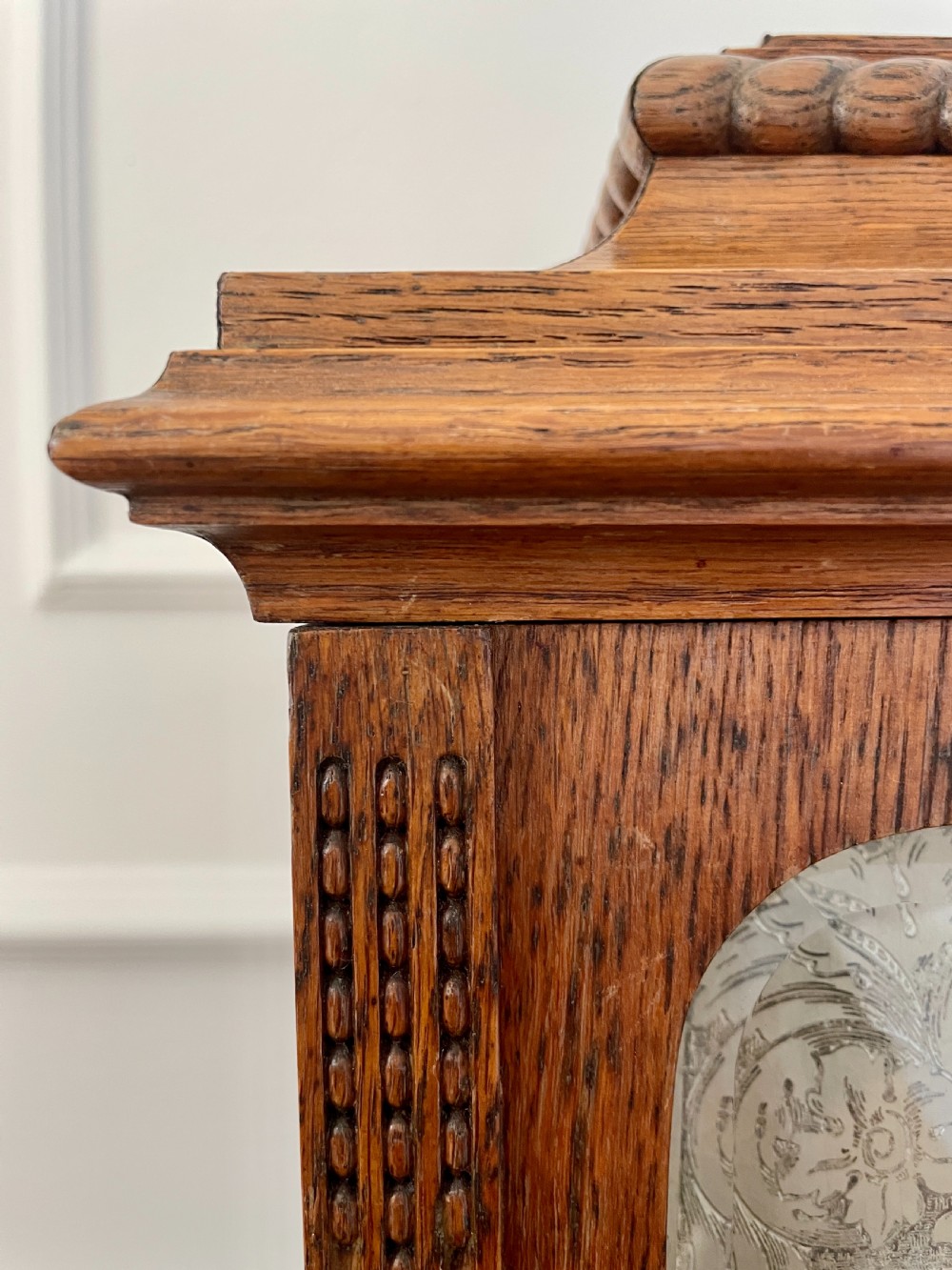 A Victorian carved oak bracket clock featuring a silvered engraved dial with Roman numerals, a chime-silent secondary dial, and carved gadrooned detailing along the top base. View XII