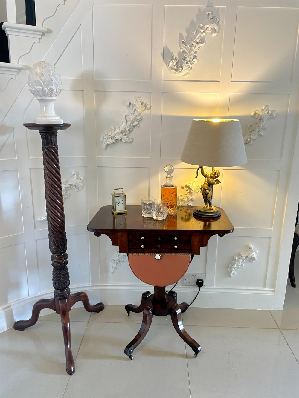 An antique Regency rosewood sewing table featuring small drop leaves, drawers with brass handles, a terracotta fabric work basket below, and a pedestal base with four splayed legs on castors. View III