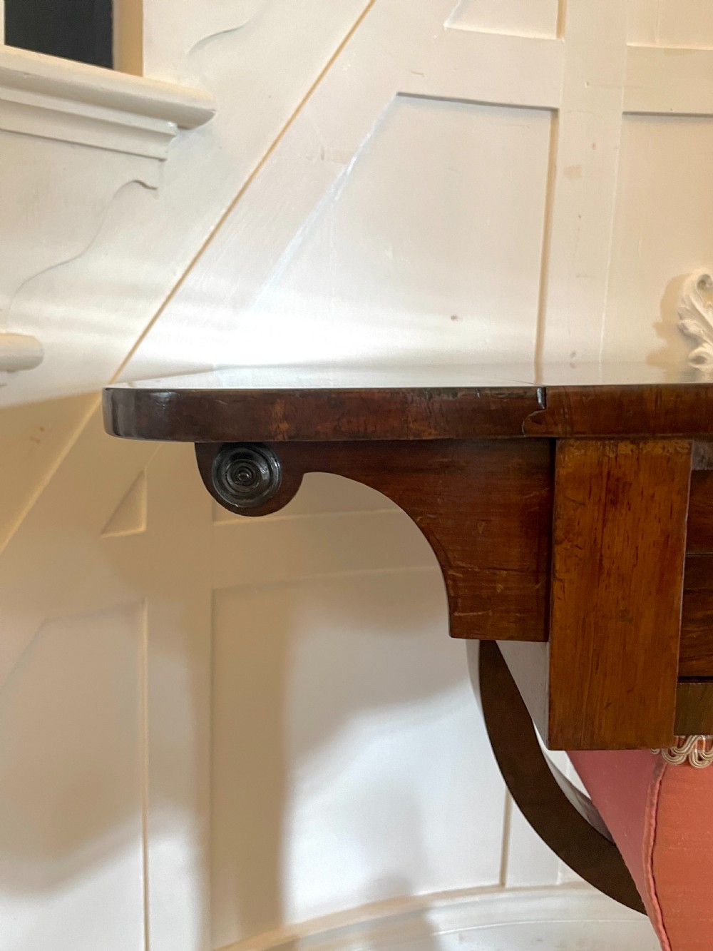 An antique Regency rosewood sewing table featuring small drop leaves, drawers with brass handles, a terracotta fabric work basket below, and a pedestal base with four splayed legs on castors. View XI