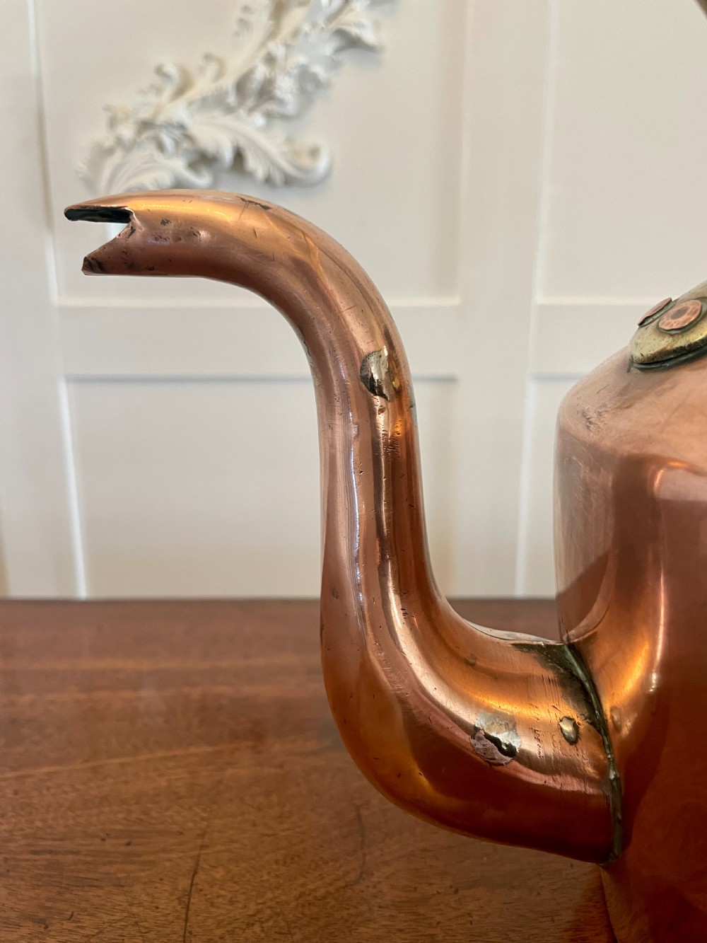 A George III copper tea kettle featuring a brass-accented overhead handle, a gooseneck spout, and a stepped lid with a brass finial. View II