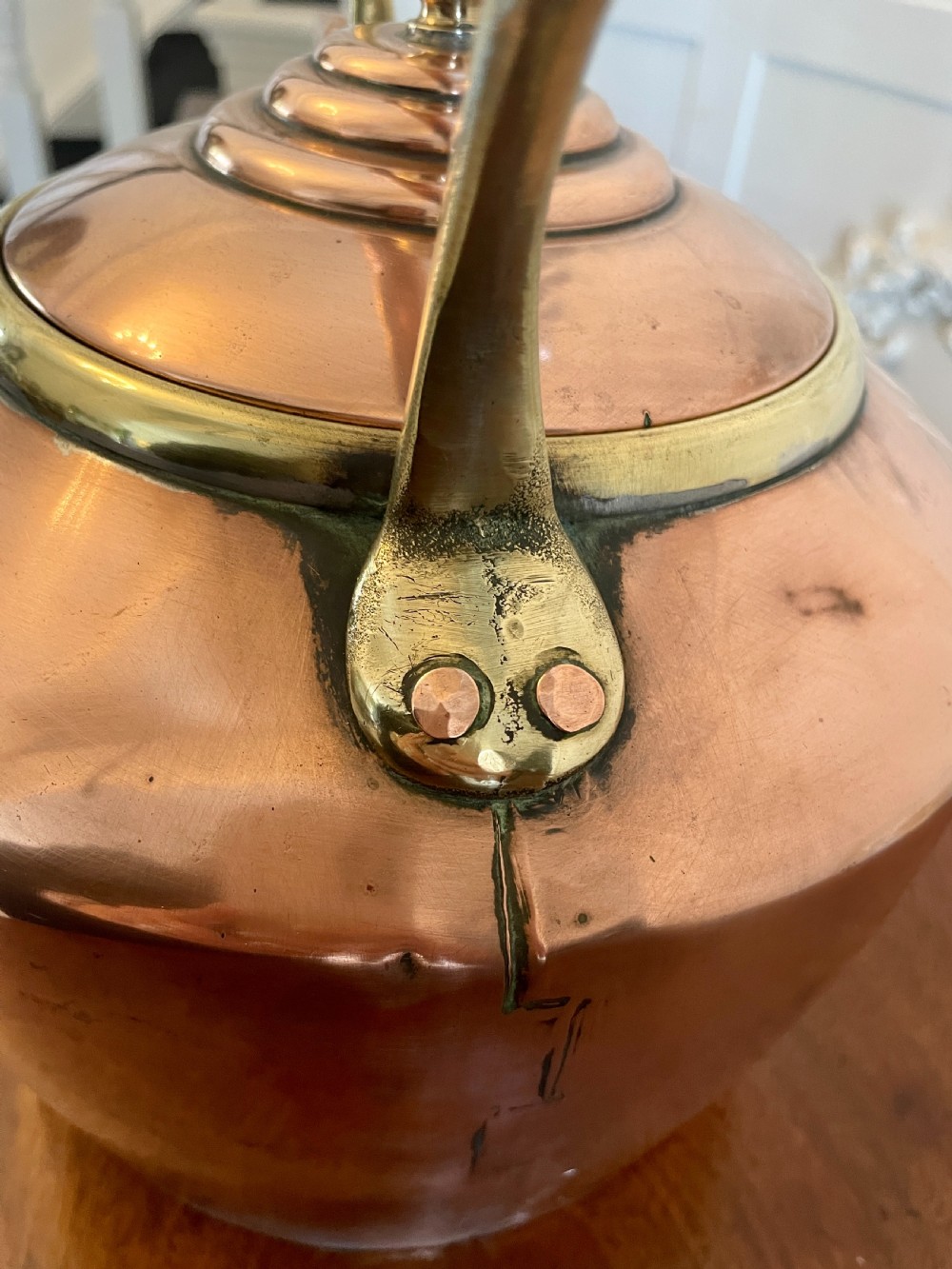 A George III copper tea kettle featuring a brass-accented overhead handle, a gooseneck spout, and a stepped lid with a brass finial. View V