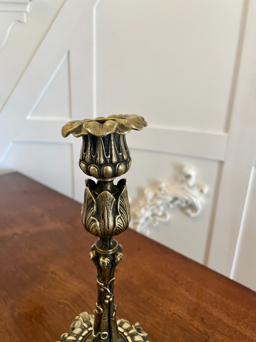 A pair of ornate brass candlesticks featuring intricate foliage carving, fluted stems, and scalloped candle sockets. View II