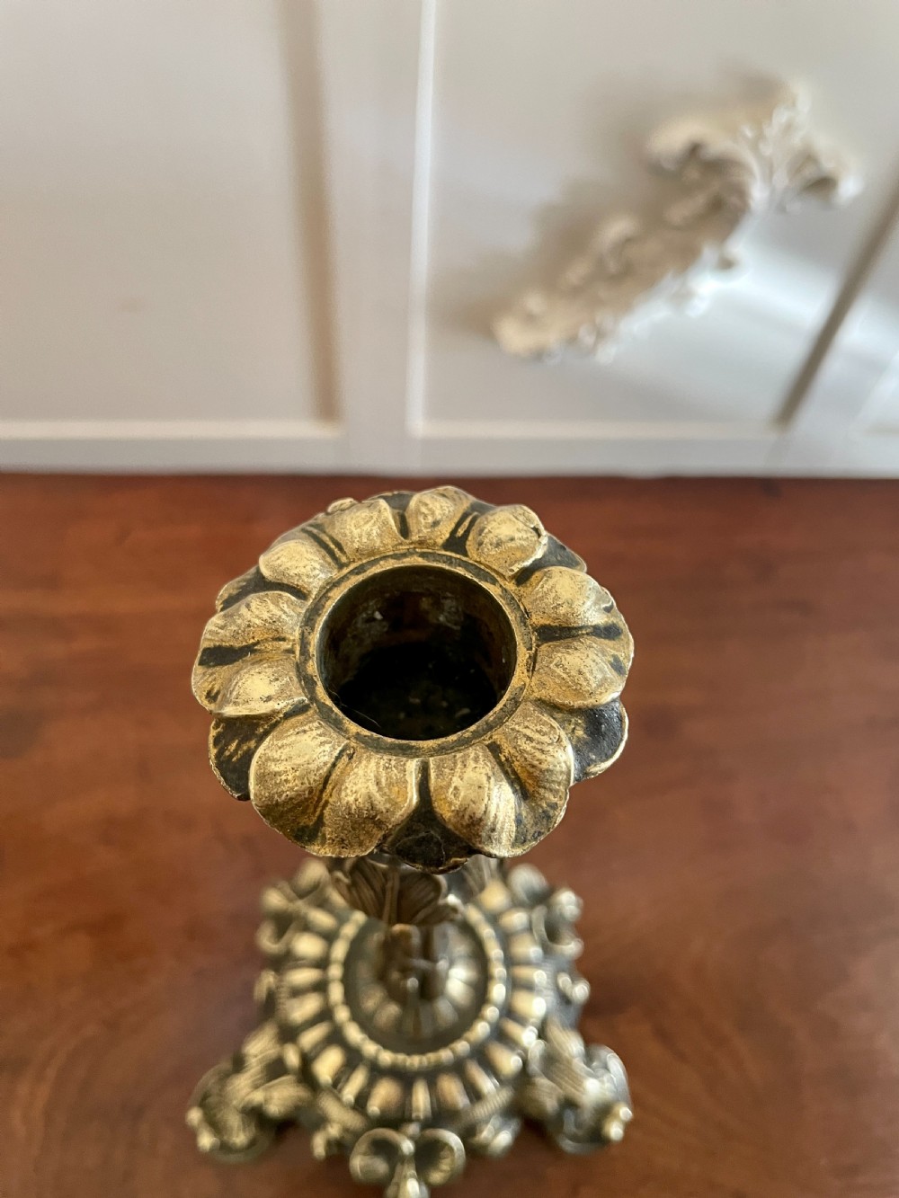 A pair of ornate brass candlesticks featuring intricate foliage carving, fluted stems, and scalloped candle sockets. View V