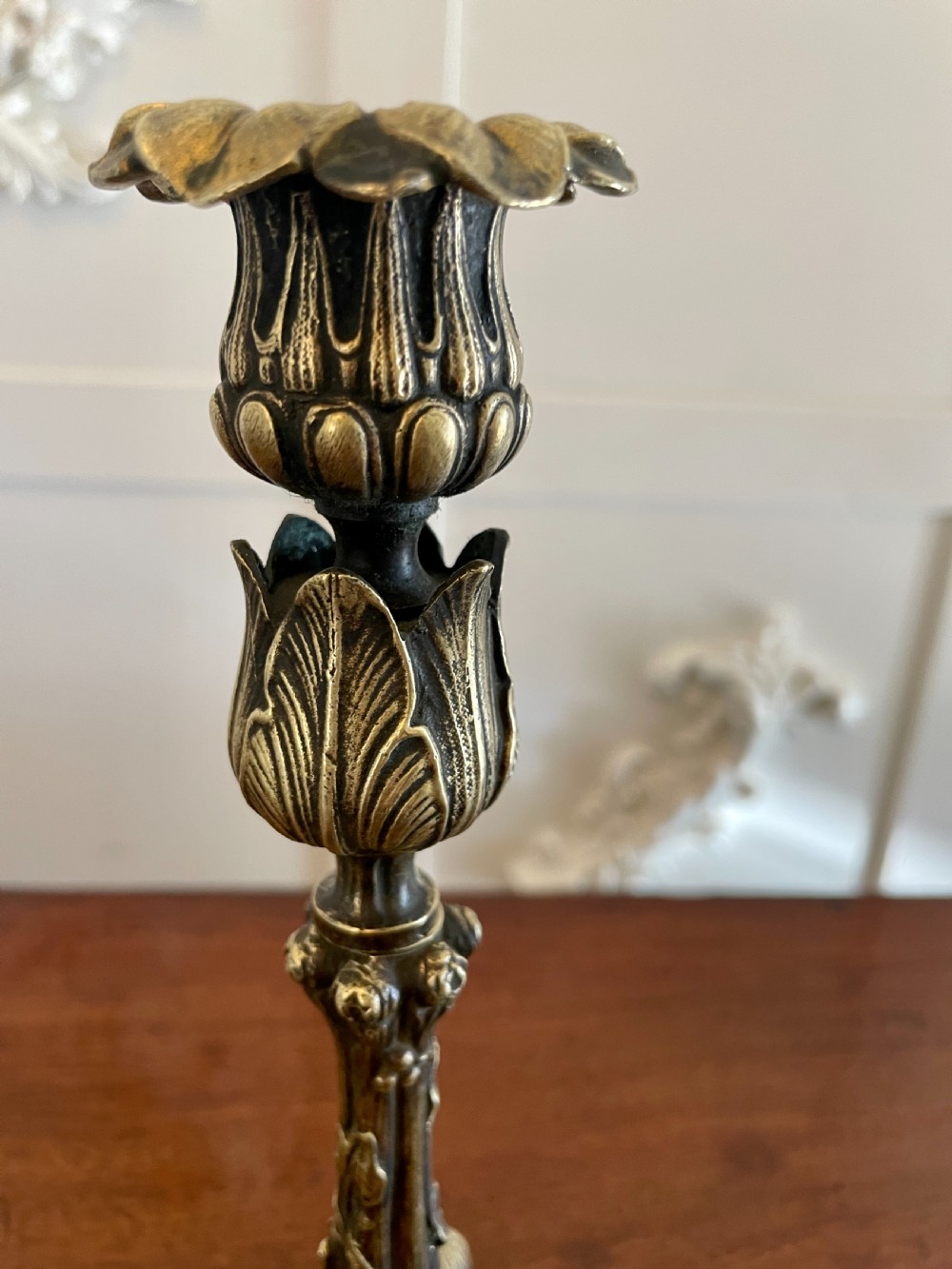 A pair of ornate brass candlesticks featuring intricate foliage carving, fluted stems, and scalloped candle sockets. View VI
