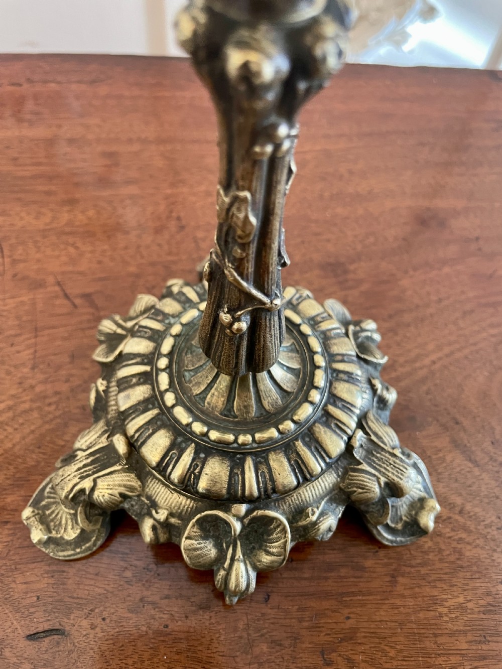 A pair of ornate brass candlesticks featuring intricate foliage carving, fluted stems, and scalloped candle sockets. View VII