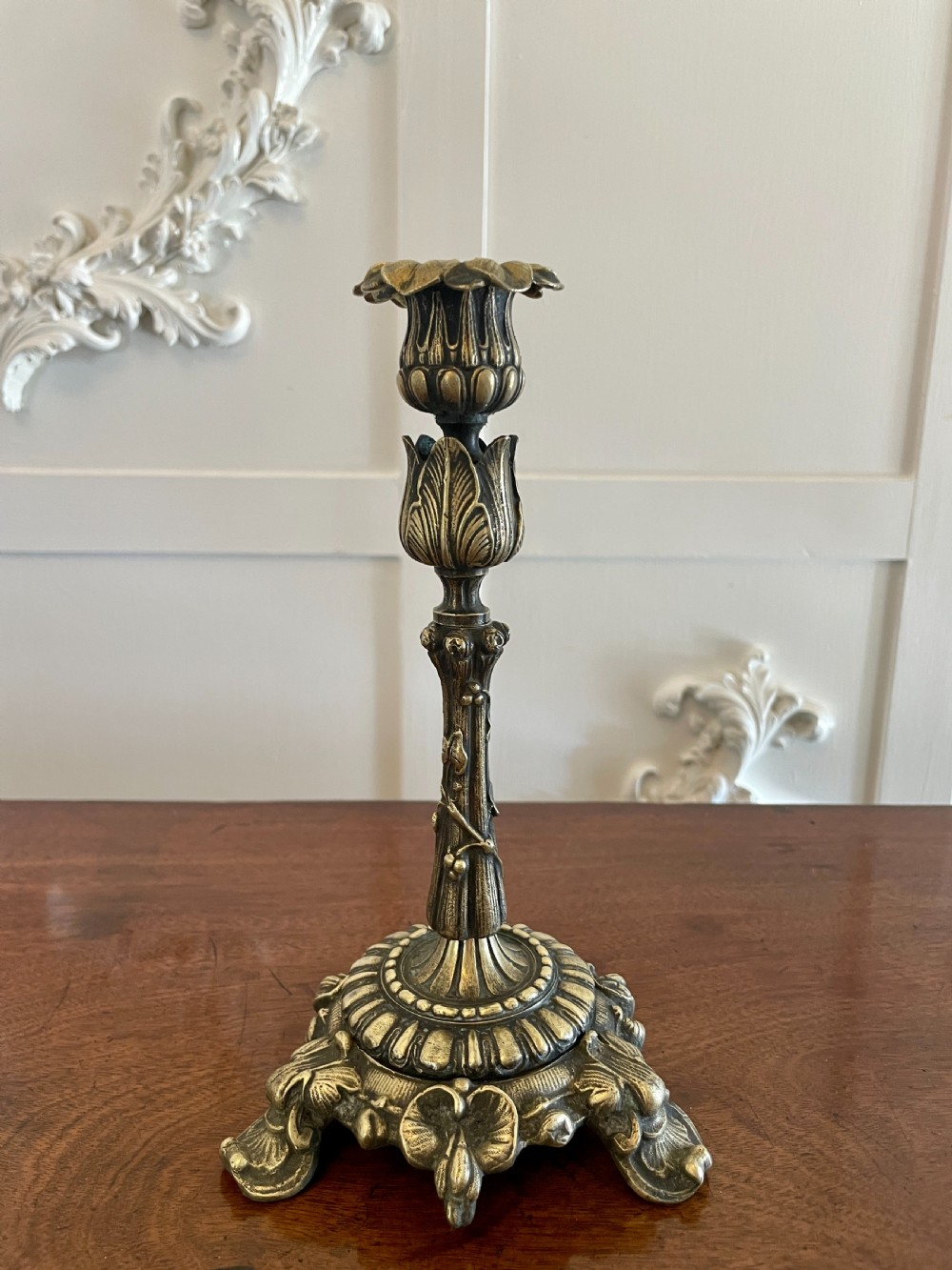 A pair of ornate brass candlesticks featuring intricate foliage carving, fluted stems, and scalloped candle sockets. View IX