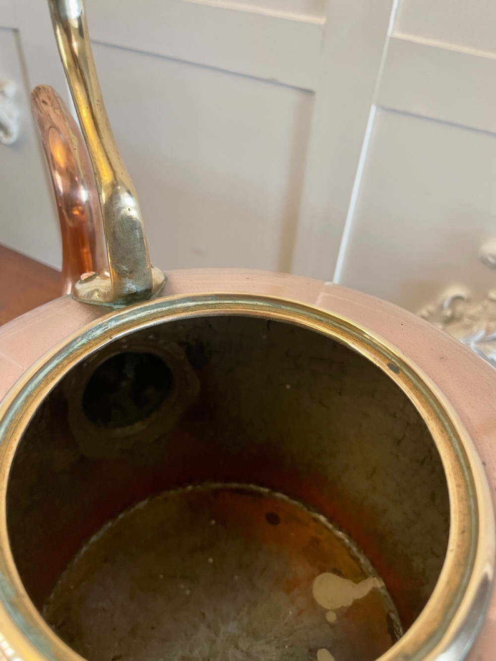 A George III copper tea kettle featuring brass handle mounts, an acorn finial, and a curved spout. View V