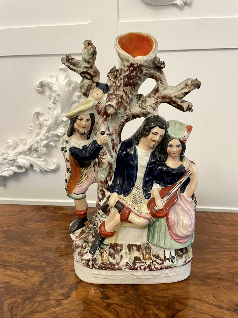 A 19th-century Staffordshire flatback pottery spill vase depicting three figures and a tree, painted in multicoloured enamels.