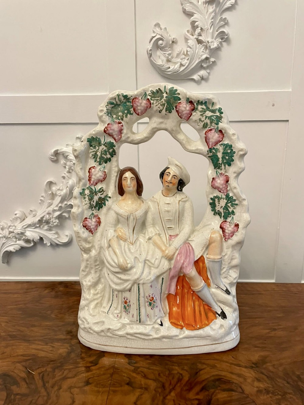 A 19th-century Staffordshire ceramic flatback figure depicting a couple framed by an arbour of leaves and fruit.