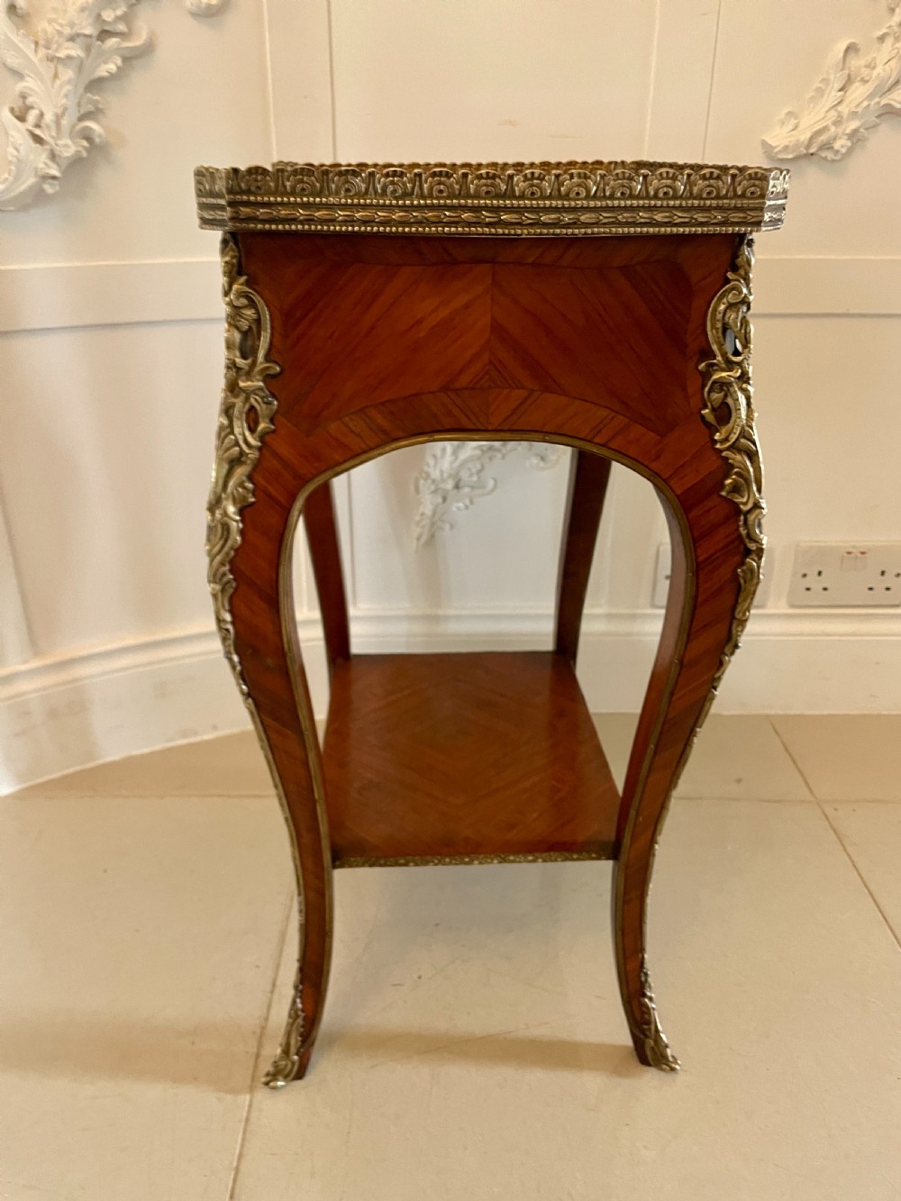A French-style kingwood lamp table featuring geometric parquetry veneer, gilt-bronze ormolu mounts on cabriole legs, a pierced brass gallery rail, and an undertier shelf. View IX