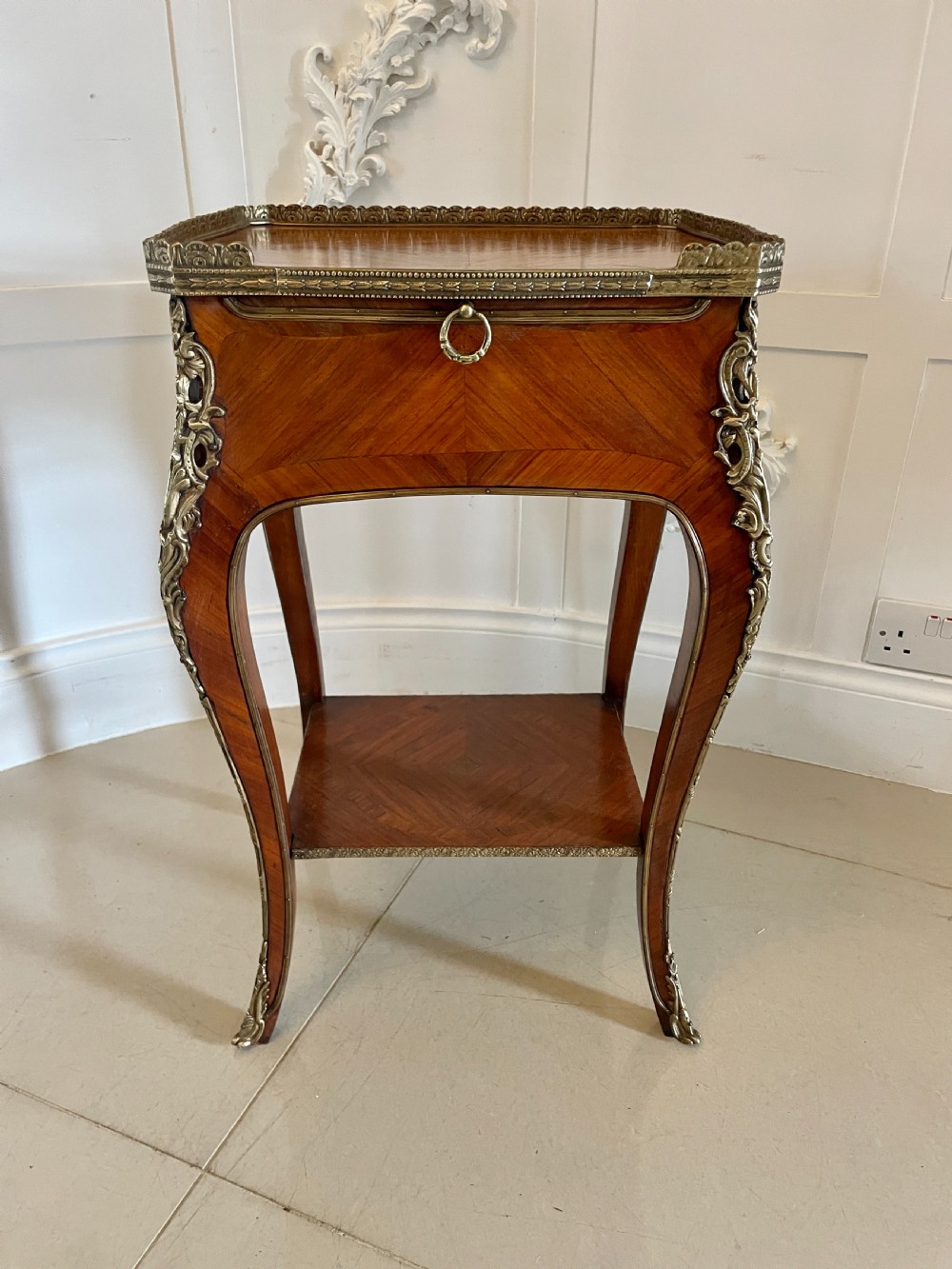 A French-style kingwood lamp table featuring geometric parquetry veneer, gilt-bronze ormolu mounts on cabriole legs, a pierced brass gallery rail, and an undertier shelf. View XIV