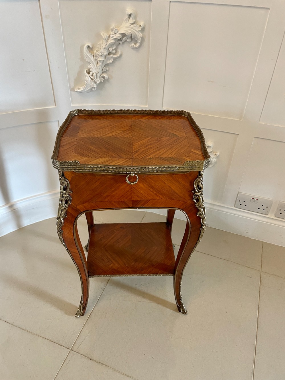 A French-style kingwood lamp table featuring geometric parquetry veneer, gilt-bronze ormolu mounts on cabriole legs, a pierced brass gallery rail, and an undertier shelf. View XV