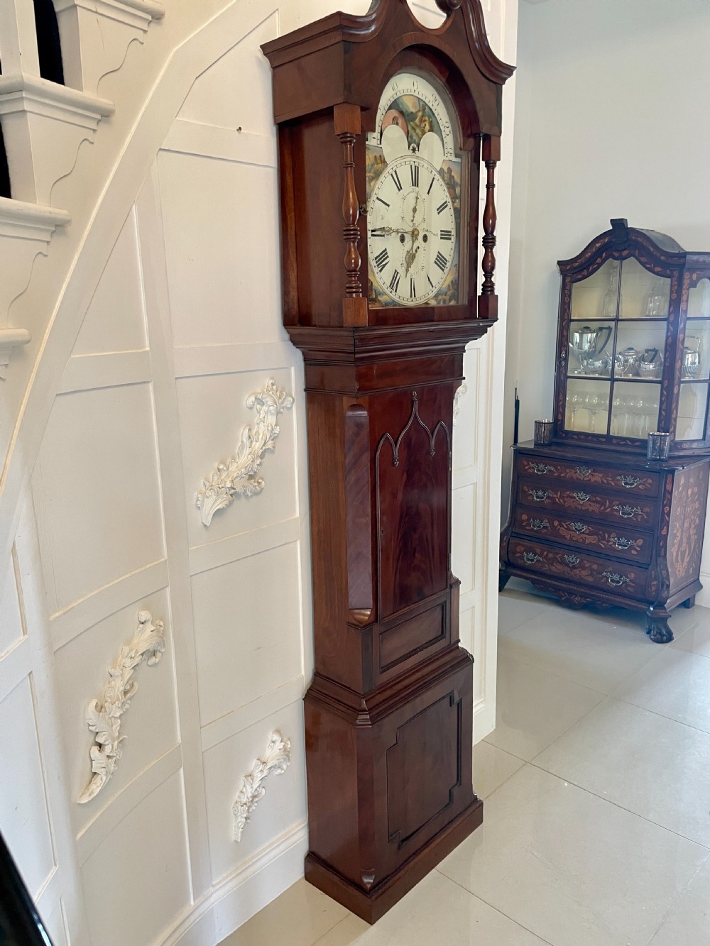 A George III mahogany eight-day longcase clock featuring a swan-neck pediment, turned hood columns, painted dial, and a shaped Gothic trunk door. View XIV