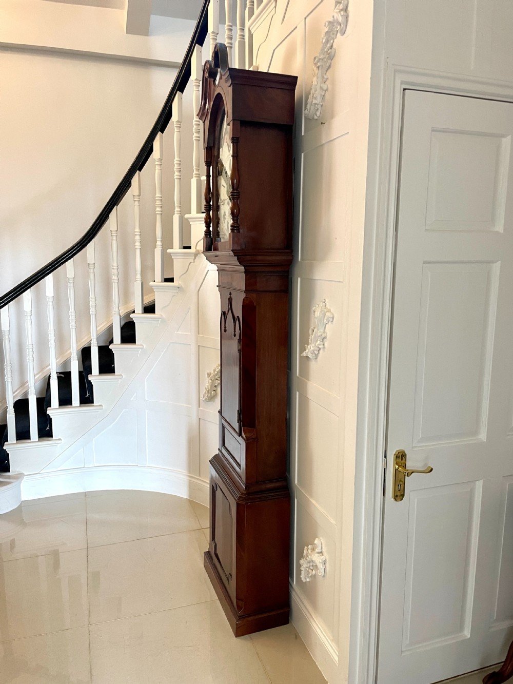 A George III mahogany eight-day longcase clock featuring a swan-neck pediment, turned hood columns, painted dial, and a shaped Gothic trunk door. View XV