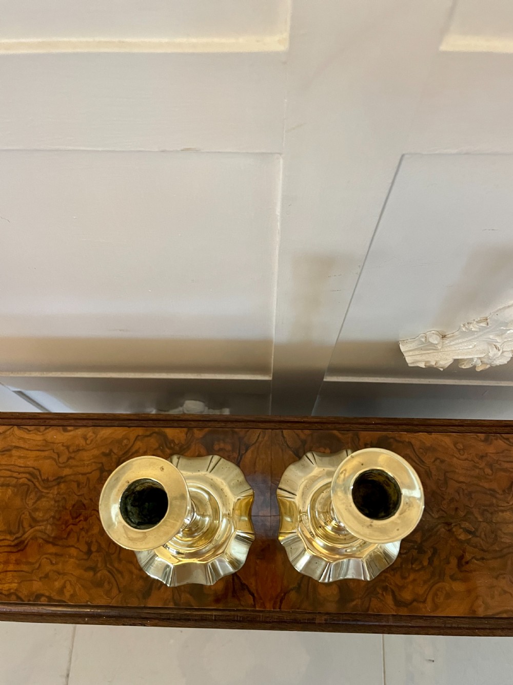 A pair of George III brass candlesticks featuring turned baluster stems and shaped scalloped bases. View V