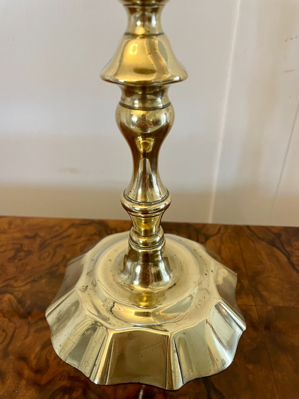 A pair of George III brass candlesticks featuring turned baluster stems and shaped scalloped bases. View VIII