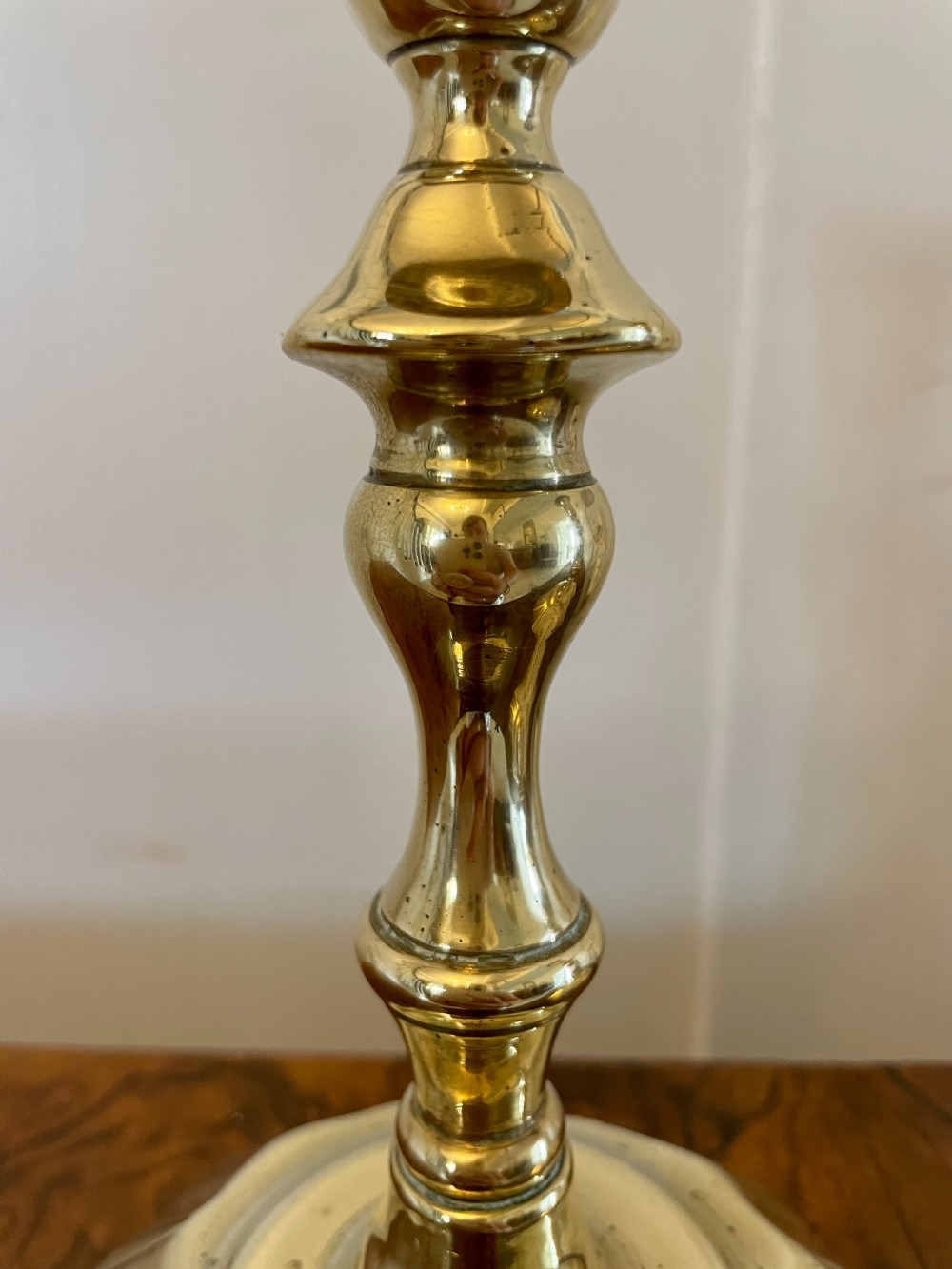 A pair of George III brass candlesticks featuring turned baluster stems and shaped scalloped bases. View IX