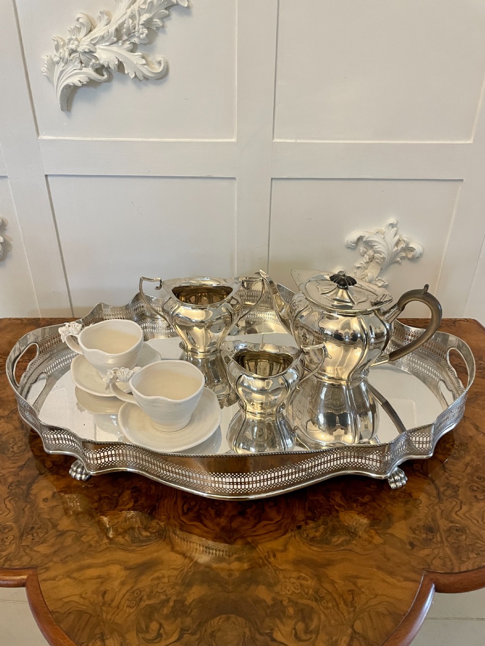 A three-piece Edwardian silver-plated tea set featuring a fluted teapot with a dark wooden handle, a matching double-handled sugar bowl, and a cream jug. View III