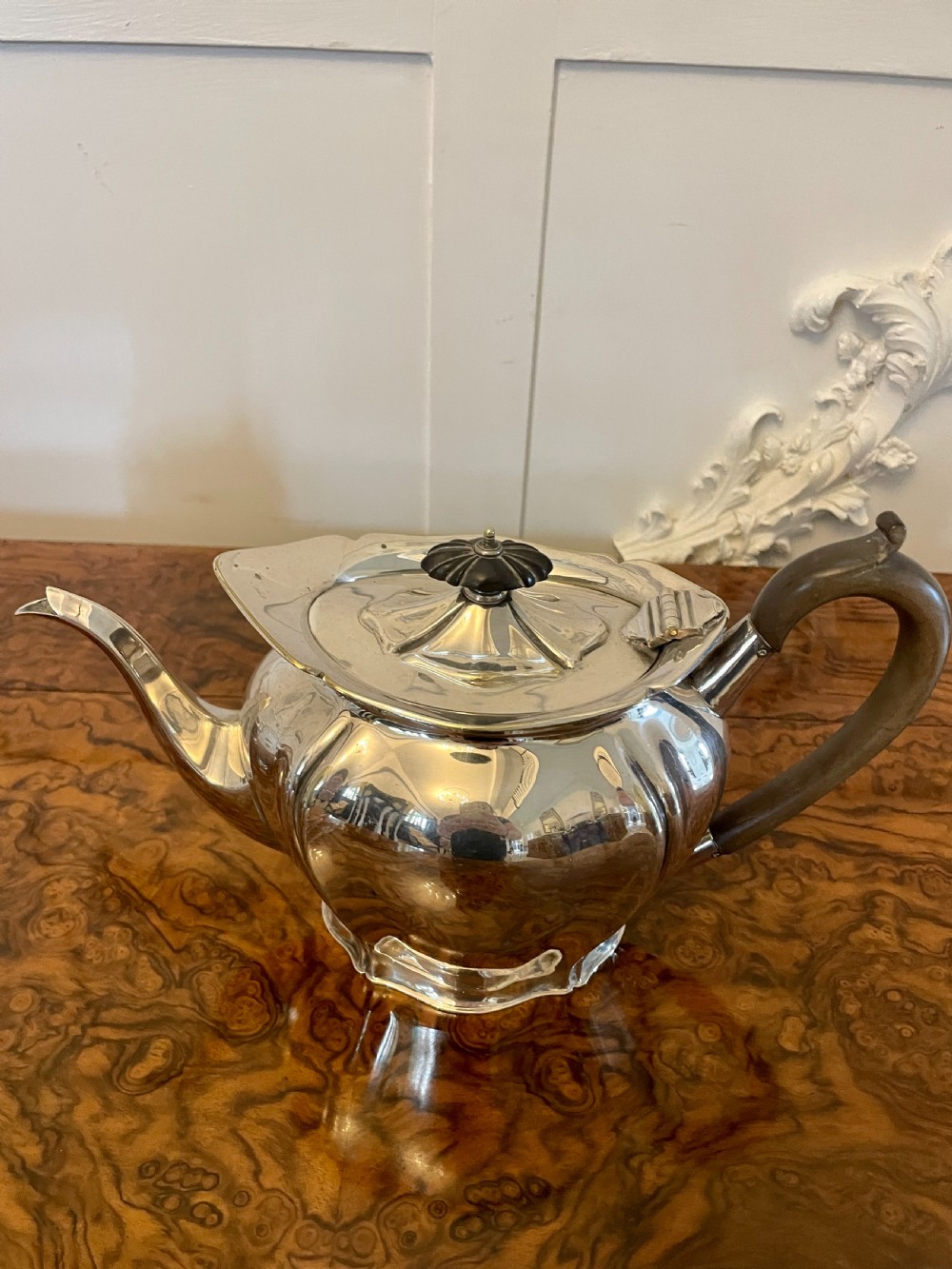 A three-piece Edwardian silver-plated tea set featuring a fluted teapot with a dark wooden handle, a matching double-handled sugar bowl, and a cream jug. View VIII