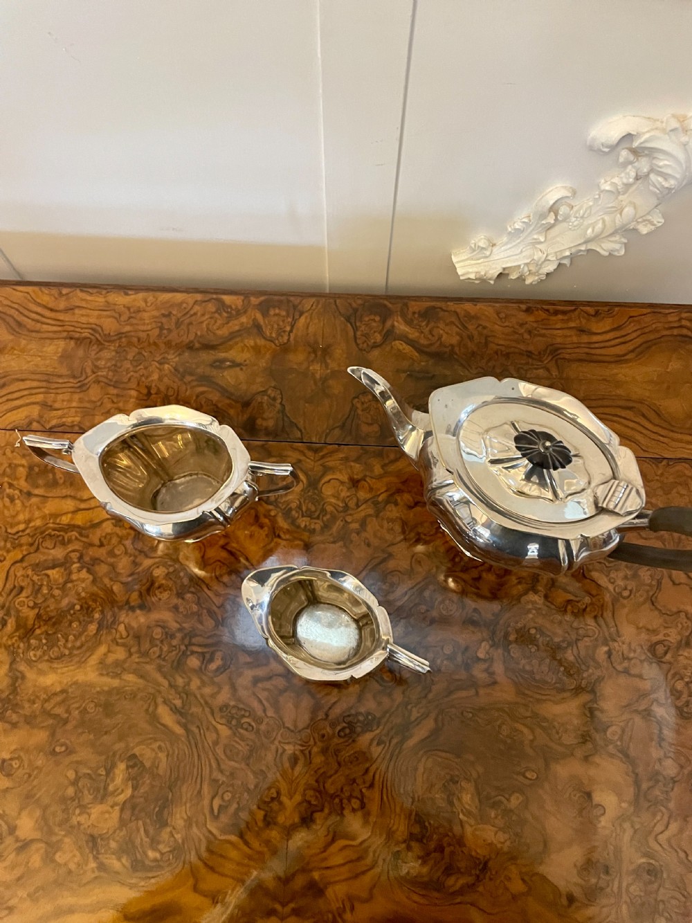 A three-piece Edwardian silver-plated tea set featuring a fluted teapot with a dark wooden handle, a matching double-handled sugar bowl, and a cream jug. View XIII