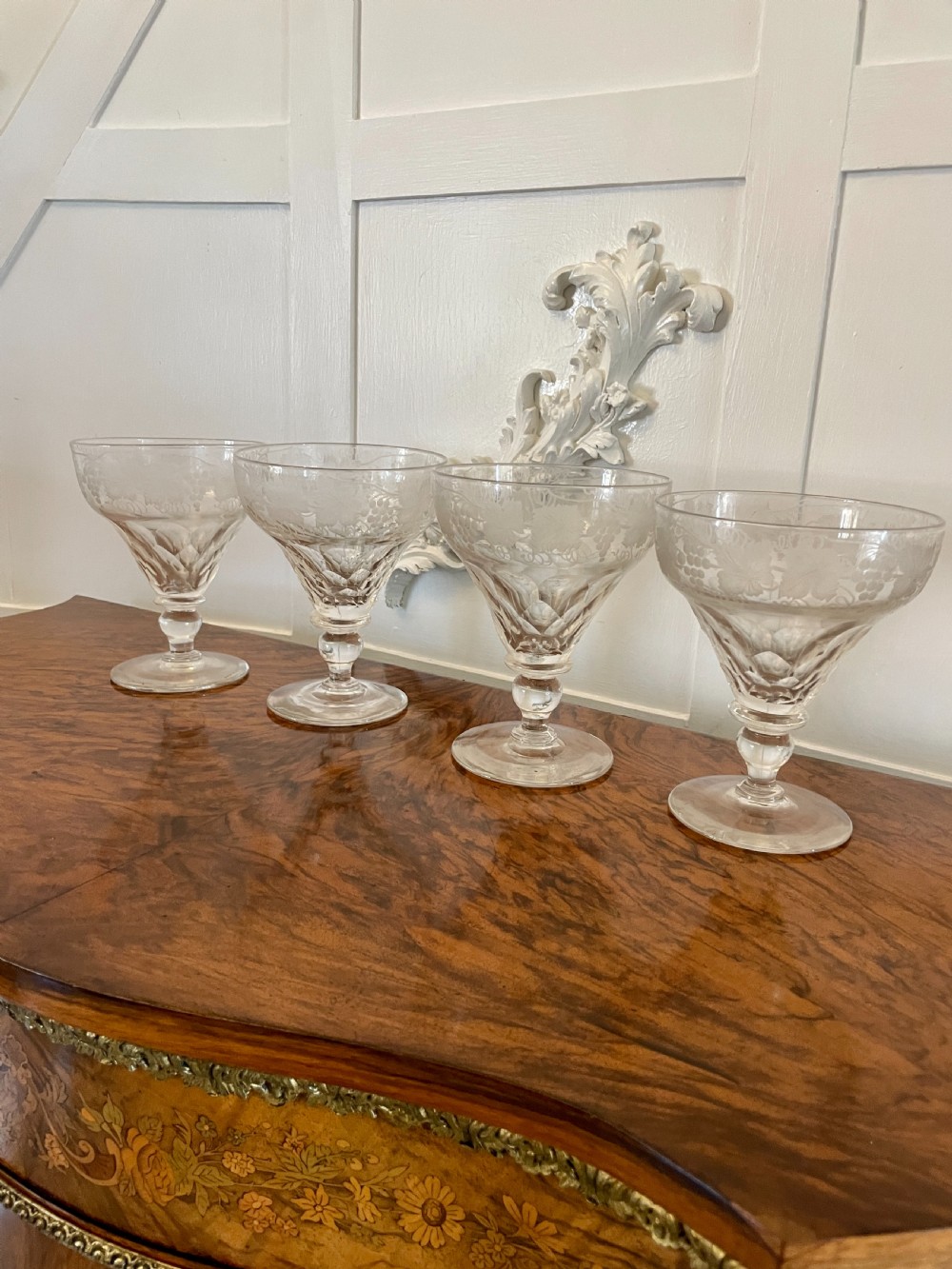 A set of four clear Victorian stemware glasses featuring detailed wheel-engraved grapevine motifs around the bowl and cut glass facets above a circular foot. View III