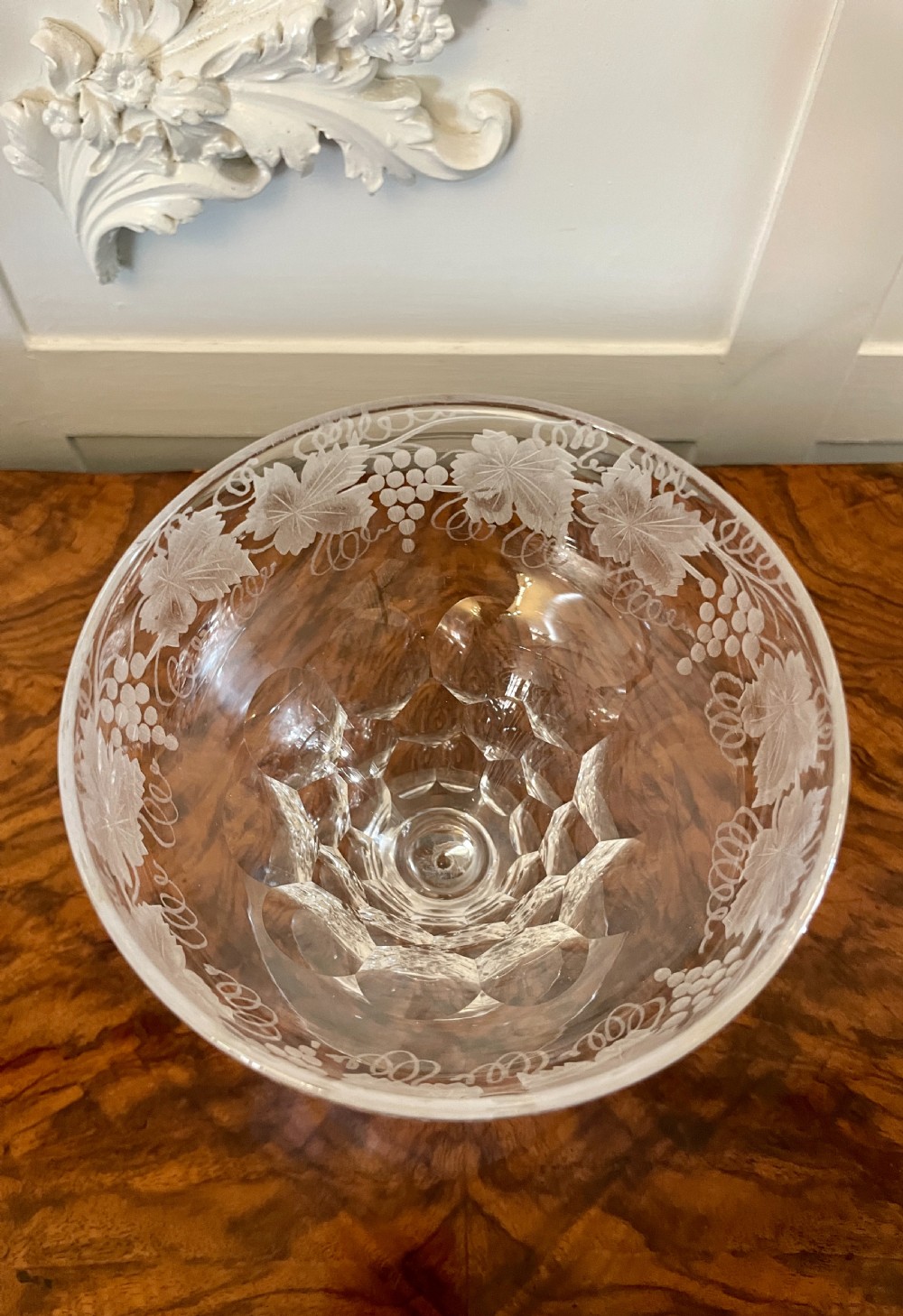 A set of four clear Victorian stemware glasses featuring detailed wheel-engraved grapevine motifs around the bowl and cut glass facets above a circular foot. View VI