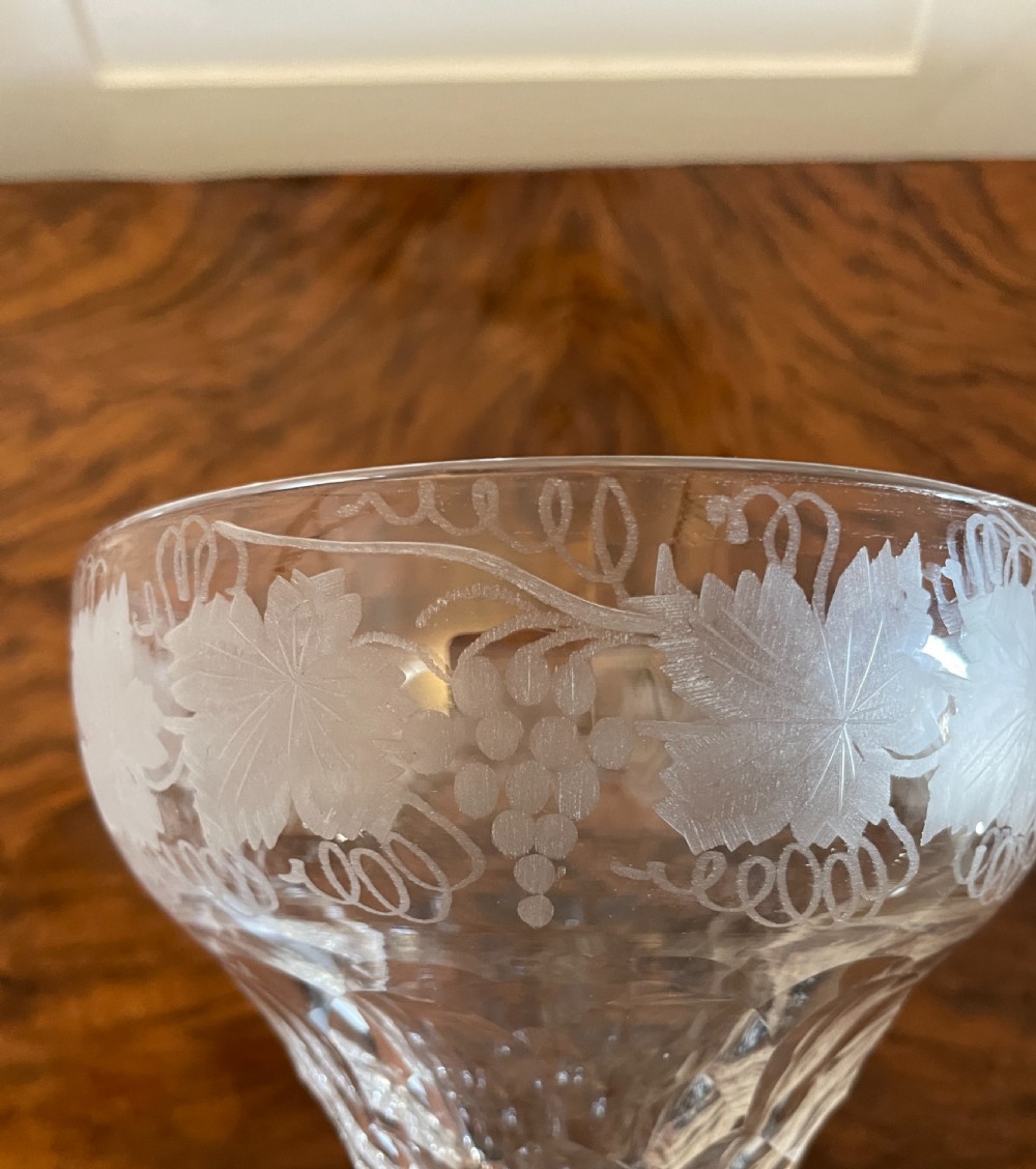 A set of four clear Victorian stemware glasses featuring detailed wheel-engraved grapevine motifs around the bowl and cut glass facets above a circular foot. View VIII