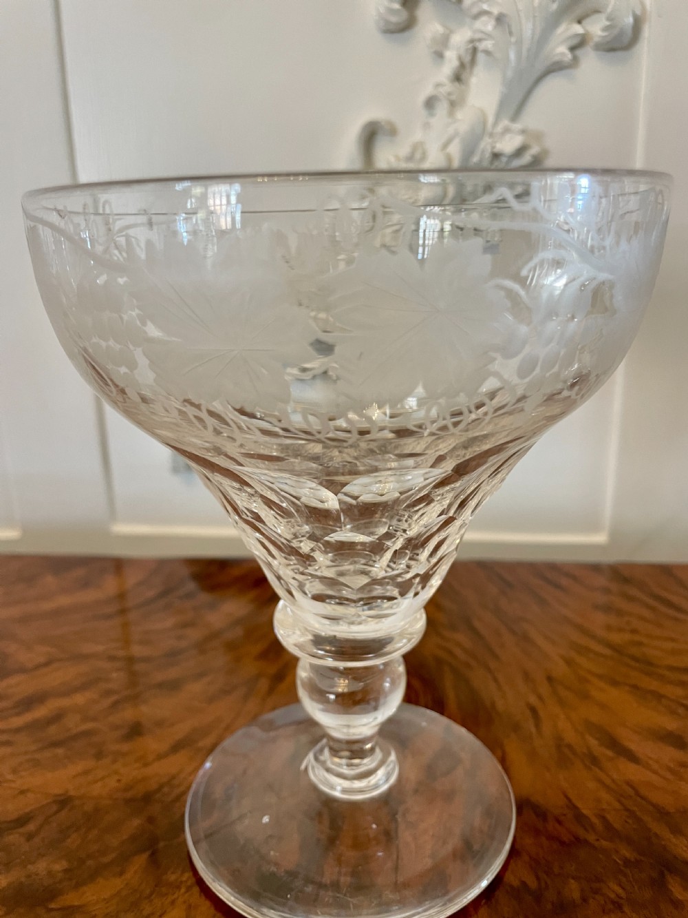 A set of four clear Victorian stemware glasses featuring detailed wheel-engraved grapevine motifs around the bowl and cut glass facets above a circular foot. View IX
