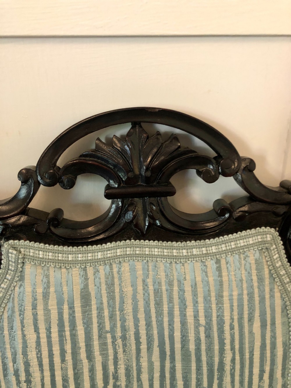 A pair of Victorian carved black lacquered open armchairs featuring oval padded backrests, curved padded arms, pale green striped fabric, and cabriole legs with brass castors. View IX