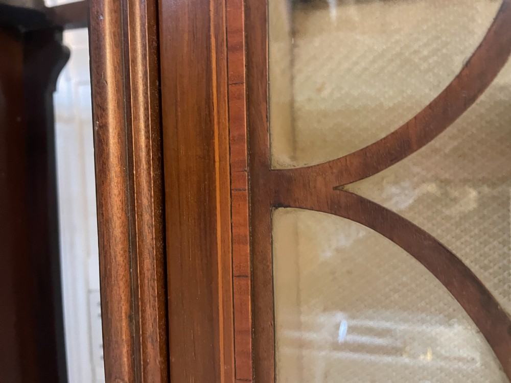 An Edwardian inlaid mahogany display cabinet featuring glazed doors with astragal bars, a central marquetry medallion, interior shelves, and a bottom undertier. View II