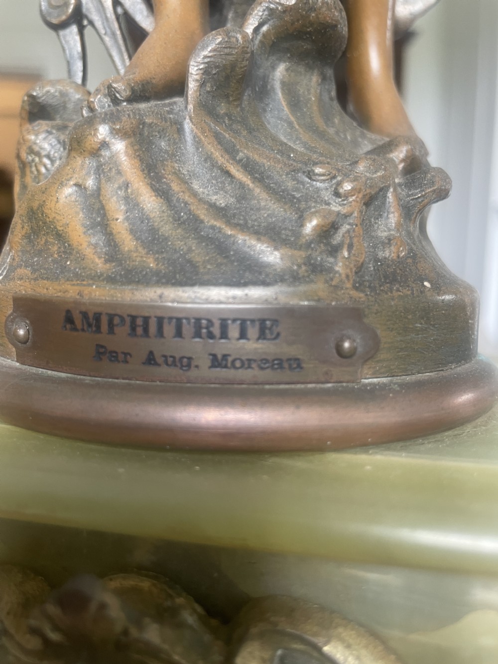 An antique French mantel clock featuring a pale green onyx base with ornate cast metal feet, housing a white enamel dial, and topped with a spelter figure of Amphitrite after Auguste Moreau. View XI