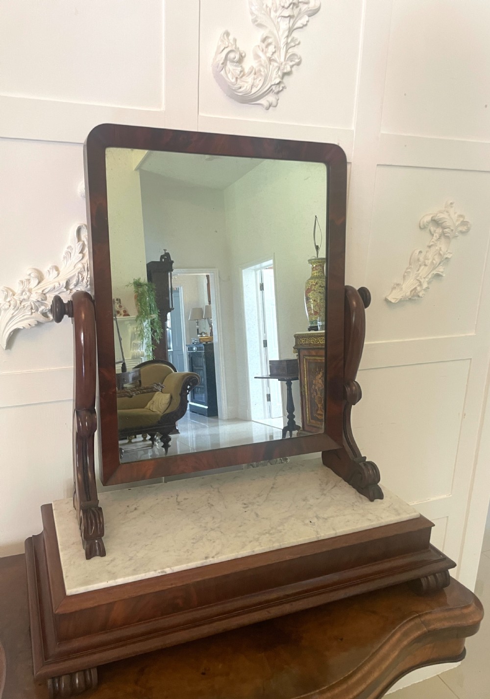 Victorian mahogany swing mirror featuring a rectangular frame set between carved scroll uprights above a white marble inset base.