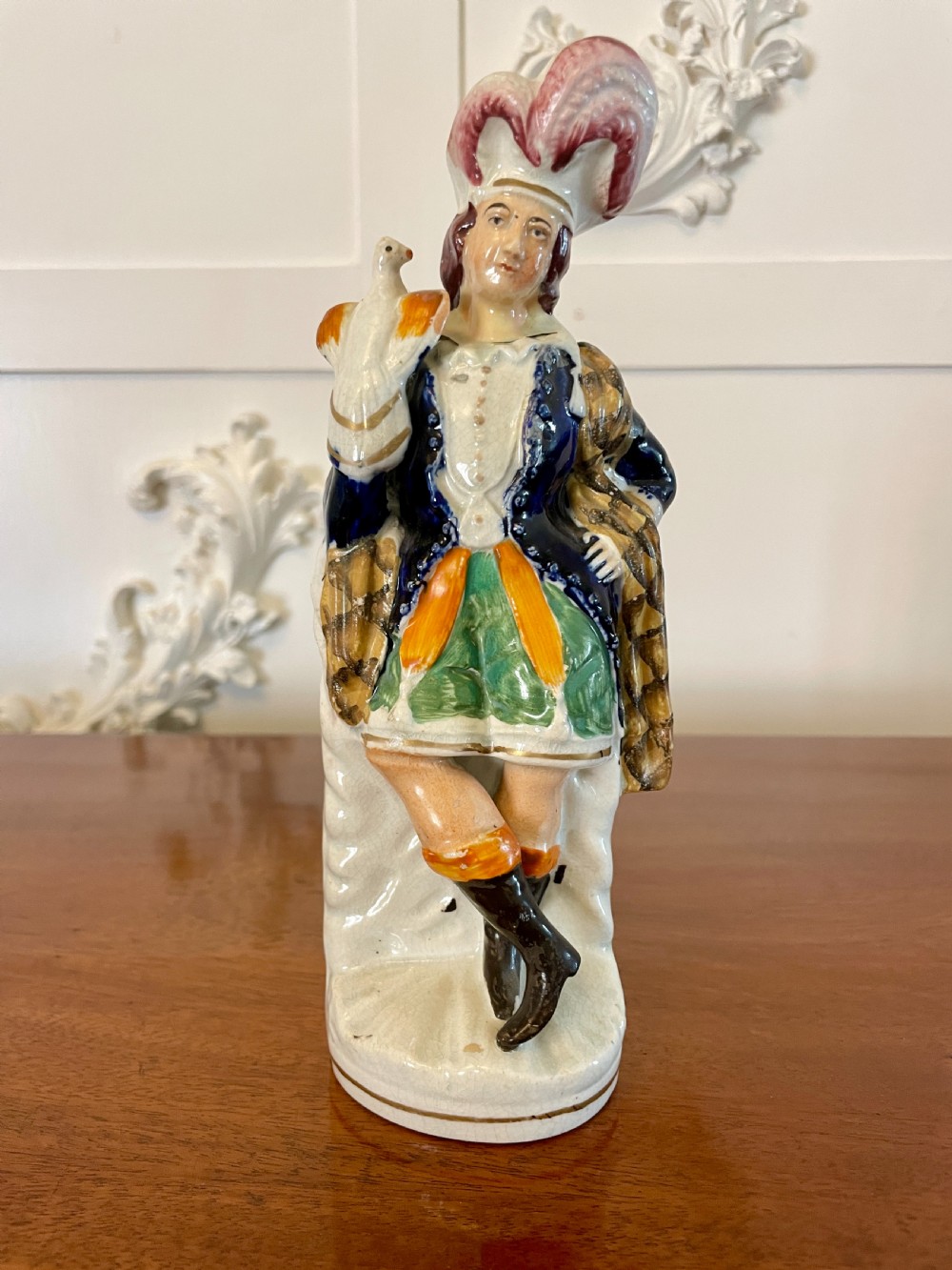 A Victorian Staffordshire earthenware flatback figure depicting a male standing character with a bird perched on his gloved hand, decorated in blue, green, orange, and white enamels. View V