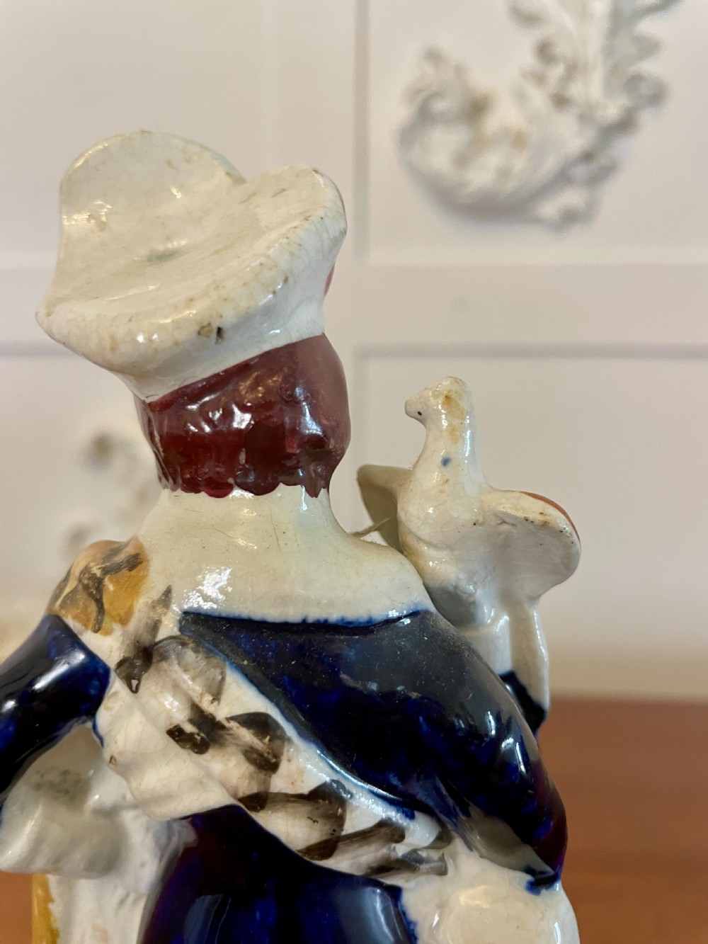 A Victorian Staffordshire earthenware flatback figure depicting a male standing character with a bird perched on his gloved hand, decorated in blue, green, orange, and white enamels. View II