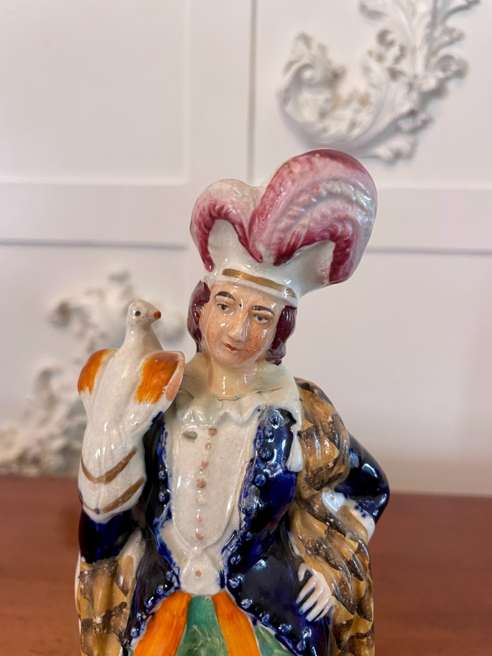 A Victorian Staffordshire earthenware flatback figure depicting a male standing character with a bird perched on his gloved hand, decorated in blue, green, orange, and white enamels. View VI